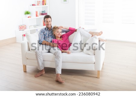 handsome couple relaxing barefoot on a white sofa in their modern living room