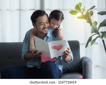 Handsome Dad and cute girl reading gift card with love and happiness. Little daughter hugging father from backside after giving card and gift to father. - Shutterstock ID 2147710419
