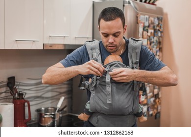 Handsome Dad In Kitchen With Baby Carrier. Father With Newborn At Home