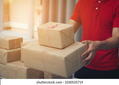 Handsome Deliver Male In Red Uniform POSTAL DELIVERY Courier MAN In Front Of CARGO Delivering Package. Fast And Free Delivery TRANSPORT.  Shopping Online And Express DELIVERY Theme.