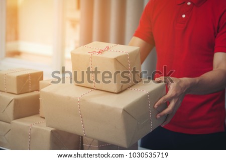 Handsome Deliver Male in Red Uniform POSTAL DELIVERY Courier MAN in Front of CARGO Delivering Package.  Fast and Free Delivery Transport. Shopping Online and Express DELIVERY Theme. warehouse,