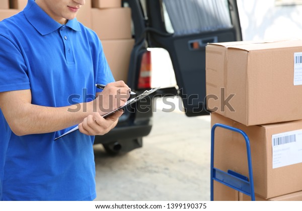 Handsome delivery\
man with clipboard\
outdoors