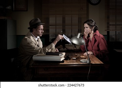 Handsome Detective At Office Desk Showing A Picture To A Young Woman, Film Noir Scene.