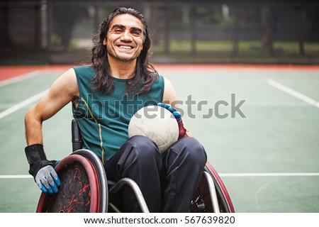 handsome determined disabled rugby player in a wheelchair on a stadium 