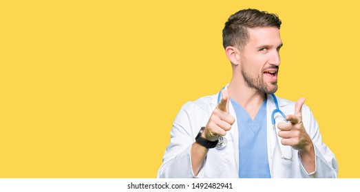 Handsome doctor man wearing medical uniform over isolated background pointing fingers to camera with happy and funny face. Good energy and vibes.