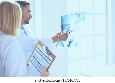 Handsome doctor is talking with young female doctor and making notes while sitting in his office. - Shutterstock ID 1175107705