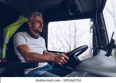 A handsome driver behind the wheel of a truck is driving on the road.