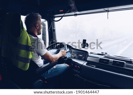 Handsome driver at the wheel of a truck at work.