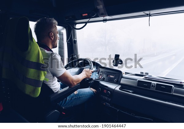 Handsome driver\
at the wheel of a truck at\
work.