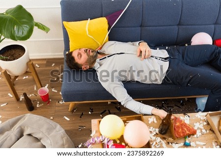 Handsome drunk man sleeping on the couch unconscious after drinking a lot of alcohol while celebrating a birthday party
