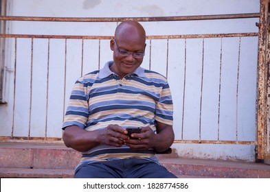 handsome elderly African man excited as he operates his phone 