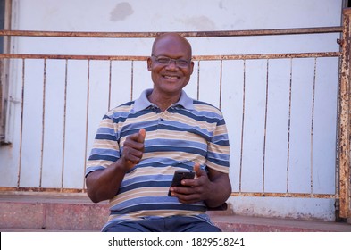 handsome elderly African man excited as he operates his phone 