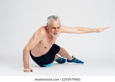 Handsome elderly man doing push ups isolated on white background. Senior male training his body, doing exercises. Motivation, hobby, healthy lifestyle