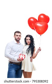 Handsome elegant guy is presenting a heart shaped gift and balloons to his beautiful girlfriend and smiling, valentines day theme. isolated on white background - Shutterstock ID 795308392