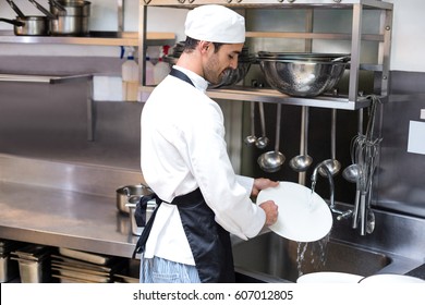 Handsome employee doing dishes in commercial kitchen