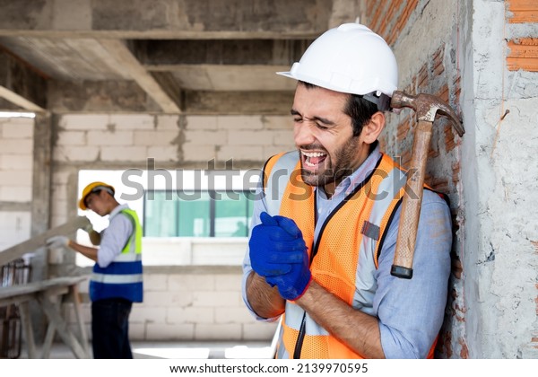Handsome engineer man\
injured his wrist when he using hammer hit on a nail while repair a\
house project. Concept of occupational safety and occupational\
accident insurance