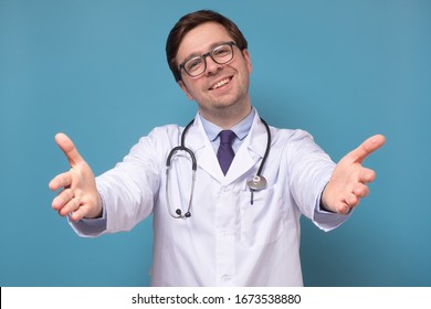 Handsome Enthusiastic And Caring European Intern Or Doctor Pulling Hands Towards Camera And Smiling Friendly At Camera Wanting Hug Or Cuddle Welcoming Friend