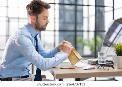 Handsome Entrepreneur Opening A Padded Envelope In A Desktop At Office.