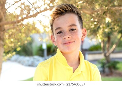 Handsome European Boy In Yellow T-shirt With An Earring In His Ear. Portrait Of Child In The Park, Summer, Sunny Day. Kid Of School Age With Stylish Haircut And Bleached Hair. Eye Contact. Life Style.