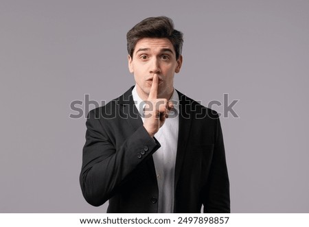 Handsome european brunette businessman with gesture of shhh, secret, silence, conspiracy, gossip concept. Smiling boss leader man holding finger on lips, white studio background. High quality