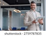Handsome executive standing with tablet, checking data, presenting business ideas, success in technology and communications