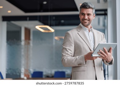 Handsome executive standing with tablet, checking data, presenting business ideas, success in technology and communications