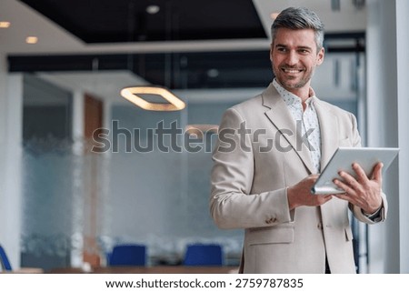 Handsome executive standing with tablet, checking data, presenting business ideas, success in technology and communications