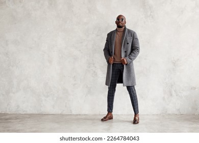 Handsome fashion man in turtleneck, gray coat, plaid trousers and leather loafer boots stands isolated on wall background, copy space. Fashionable male model - Shutterstock ID 2264784043
