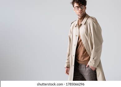 handsome, fashionable man holding hand in pocket and looking away isolated on grey