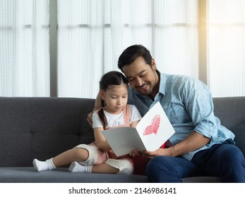 Handsome Father And Cute Daughter Looking At Card, Reading Together. Father's Day Or Birthday Card 