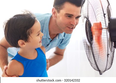 Handsome Father And  Cute Son Cooling In Front Of Fan. Hot Summer Day.