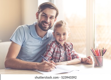 Handsome father and his cute little daughter are drawing and smiling while spending time together