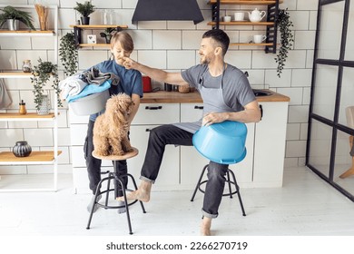 Handsome father and his teenager son spending quality time together, having fun. Men doing chores, cleaning, sorting laundry in the kitchen at home. Pet dog near them - Powered by Shutterstock