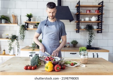 Handsome father, strong young man cooking healthy vegetable salad with fresh organic ingredients, tasty food in the kitchen at home . Men doing chores. Ripe pepper, tomato, cucumber - Shutterstock ID 2198798005