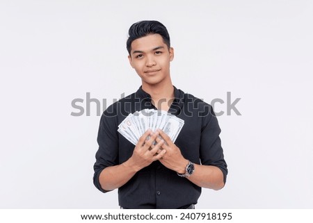A handsome filipino guy holding a wad of dollar bills. Showing off some cash. Studio shot, with white background.