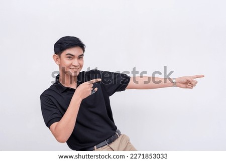 A handsome Filipino man enthusiastically points to the right with much zeal. Isolated on a white background.