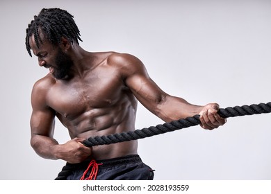 handsome fit bearded afro sportsman yelling and pulling rope isolated on white studio background. Black shirtless guy engaged in cross fit. Concept of sport, bodybuilding, healthy lifestyle. - Powered by Shutterstock