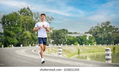 Handsome and fit millennial Asian man in sportswear running or jogging on the side path along the beautiful lake. Healthy lifestyle concept - Powered by Shutterstock