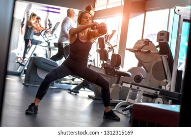 Handsome Fitness Girl Lifting Dumbells During An Exercise Class In A Gym 