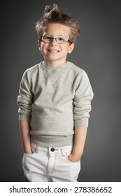 Handsome five year old boy posing in studio over gray background. Boy wearing reading glasses. 