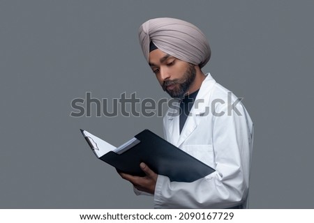 Handsome focused male doctor scrutinizing his patient files