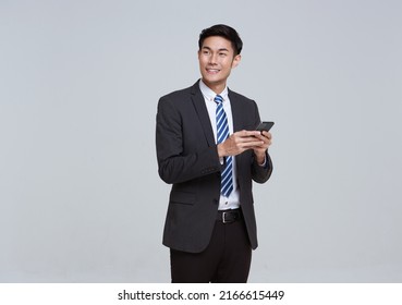 Handsome and friendly face asian businessman smile in formal suit his using smartphone on white background studio shot.