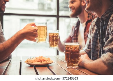 Handsome friends are drinking beer, talking and smiling while resting at the pub - Powered by Shutterstock