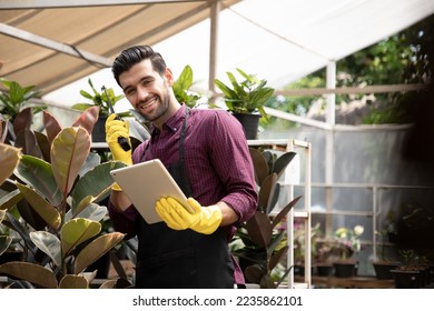 Handsome gardening call center man wearing cotton apron with digital tablet for checking order in home gardening for looking who buys the tree and ornamental. Take order for customer - Powered by Shutterstock