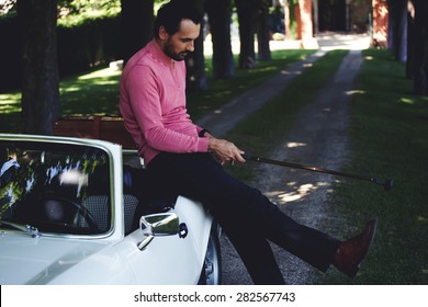 Handsome Golf Player Holding A Driver Or Golf Club While Getting Ready For A Day On The Course, Wealthy Man Leaning On His Convertible Luxury Car Preparing For Golf Game At Recreation Time On Weekend 