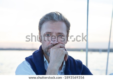 Handsome good looking mature man on the yacht. Portrait of successful man on sailing boat at sunset.