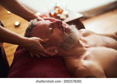 Handsome grizzled man enjoying head massage indoors - Powered by Shutterstock