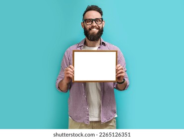 A handsome guy with a beard in eyeglasses proudly holds in his hands a frame with an empty space for your diploma, award or text. Recognition for good work