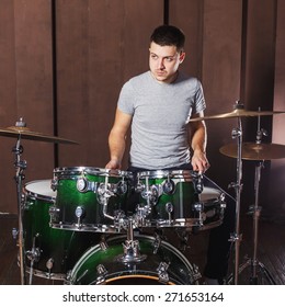 Handsome guy behind the drum kit on a brown background