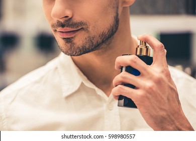 Handsome guy is choosing perfumes and smiling while doing shopping in the mall